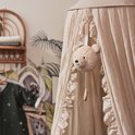 Muziekhanger teddybeer hangt in een crèmekleurige hemel met ruches.