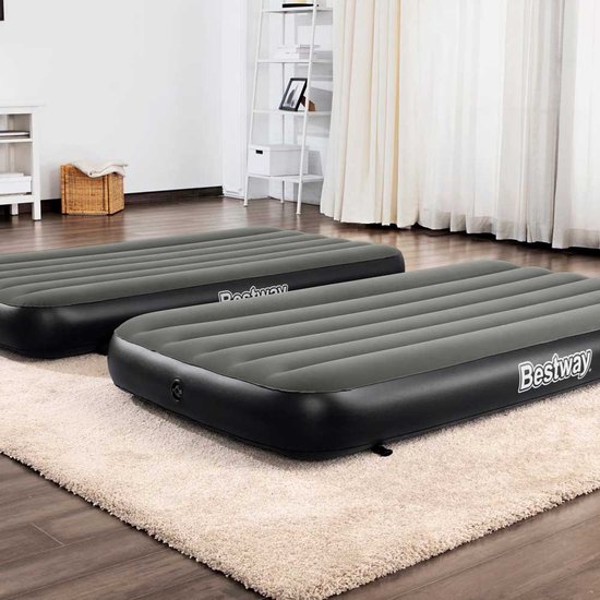Twee Bestway luchtbedden naast elkaar op een beige vloerkleed. De luchtbedden zijn donkergrijs met het Bestway logo op de zijkant.