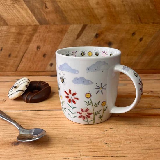 Witte mok met een kinderlijke tekening van bijen, wolken en bloemen. De mok heeft een oor.