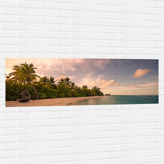 Muursticker - Ligbed aan Palmboom op Strand van Onbewoond Eiland - 150x50 cm Foto op Muursticker