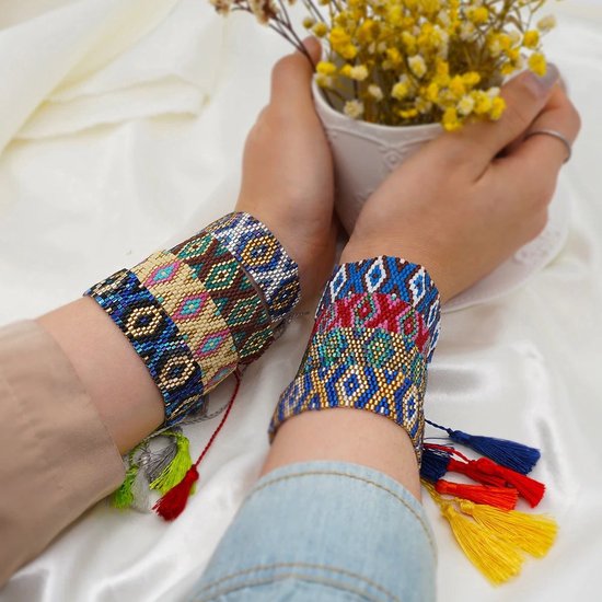 Twee handen die de Sorprese armbanden dragen. Verschillende patronen met veelkleurige kralen, zilver, goud en kwastjes in diverse kleuren.