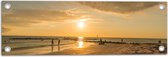 Tuinposter – Personen - Avondzon - Zee - Strand - Zand - Water - Wolken - 60x20 cm Foto op Tuinposter (wanddecoratie voor buiten en binnen)