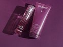 Caudalie douchegel in paarse tube en een verstuiver met paarse vloeistof, op paarse achtergrond.