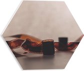 PVC Schuimplaat Hexagon - Uitgerold Filmrolletje tegen Stenen Muur - 30x26.1 cm Foto op Hexagon (Met Ophangsysteem)