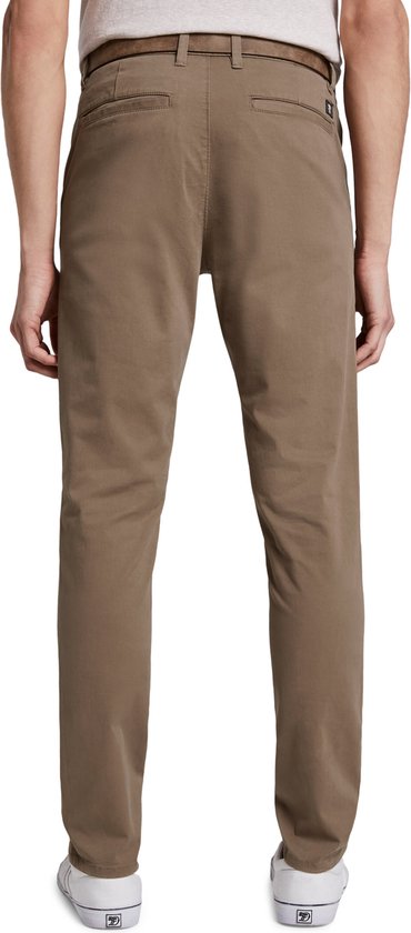 Achterkant van een lichtbruine chino broek voor heren, gedragen met witte sneakers en een bruine riem. De broek heeft een merklabel.