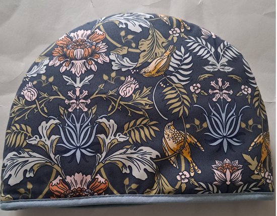 Theemuts met een donkerblauwe stof met een patroon van bloemen, bladeren en vogels.