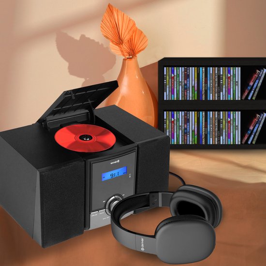Zwarte Denver micro-installatie met geopende CD-speler, rode CD, zwarte koptelefoon en een boekenkast op de achtergrond.
