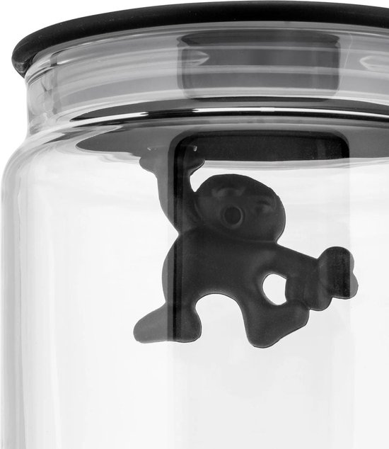 Gros plan d'une petite figurine noire accrochée au bord d'un bocal en verre.
