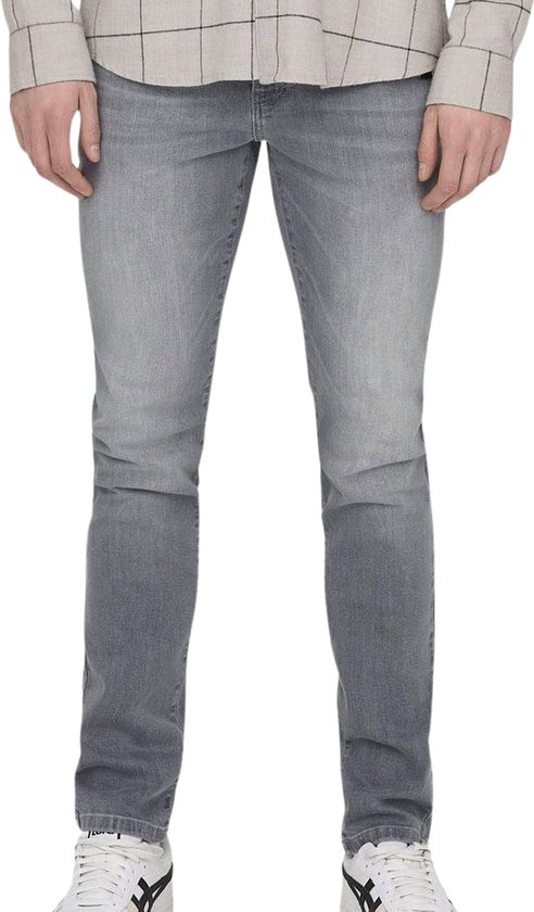 Man in slim fit grijze jeans en een geblokt shirt met bruine lijnen. Schoenen met witte veters.
