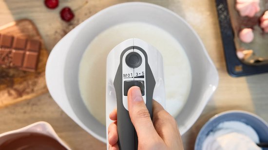 Close-up van een witte Bosch ErgoMixx handmixer die room klopt, met bedieningsknoppen zichtbaar.
