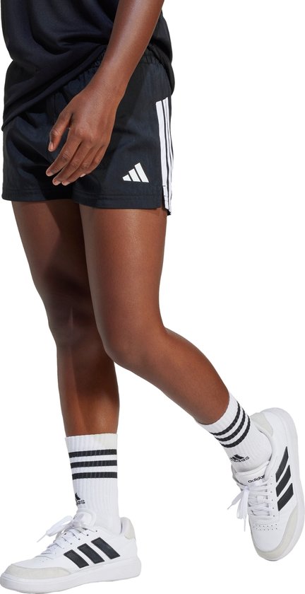 Short de sport noir avec bandes blanches Adidas sur les côtés et logo Adidas blanc sur la jambe droite.