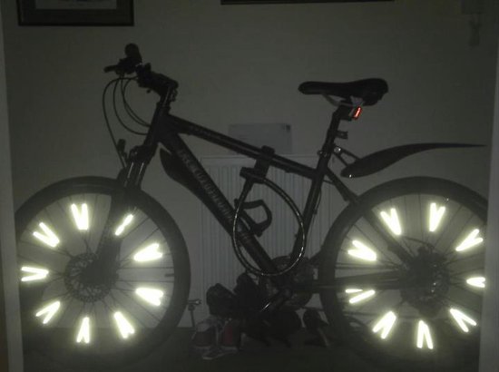 Zwarte fiets met reflectoren op de spaken in hartvorm, met slot en fietslicht.