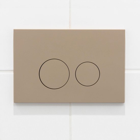 Taupe bedieningsplaat met twee ronde knoppen, een grote en een kleine, gemonteerd op witte tegels.