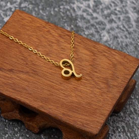 Gouden ketting met leeuw-symbool op een houten standaard.