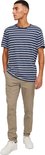 Man met gestreept blauw-wit T-shirt en beige chino broek, staand met handen in de zakken.