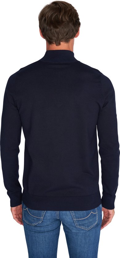 Achterkant van man in donkerblauwe trui met rits tot de borst en jeans.