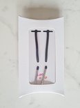 Zwarte veters met zilveren nestels op witte verpakking. Tekst 'Lace it up'.