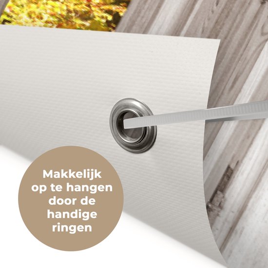 Gros plan d'une bannière de jardin avec un œillet et une bande pour l'accrocher. Texte : 'Makkelijk op te hangen door de handige ringen'.