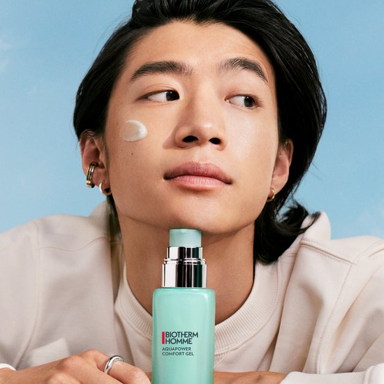 Man met een druppel BIOTHERM HOMME Aquapower Comfort Gel op zijn wang en het flesje in zijn hand