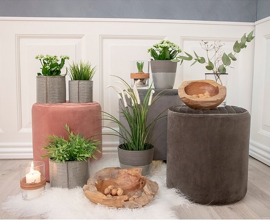 Houten schalen, plantenpotten en kussens op een witte vloer.