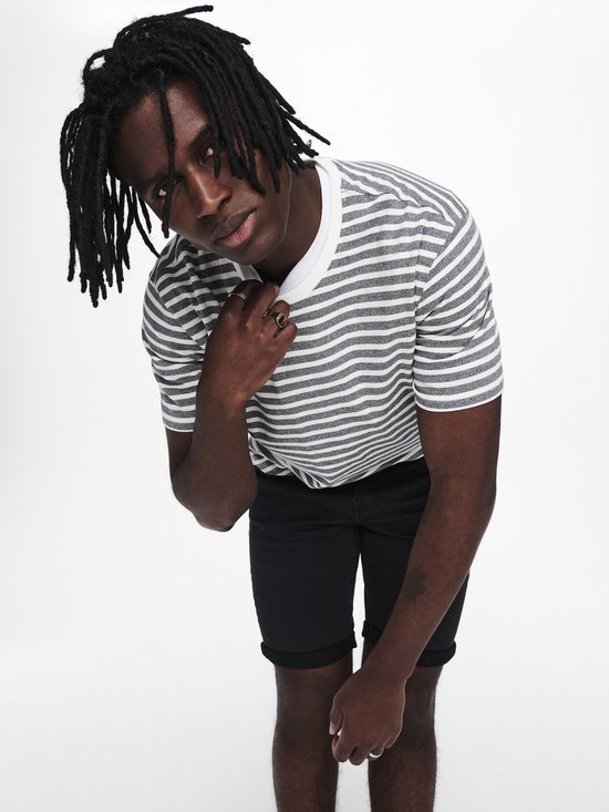 Man met dreadlocks draagt gestreepte t-shirt en zwarte shorts.