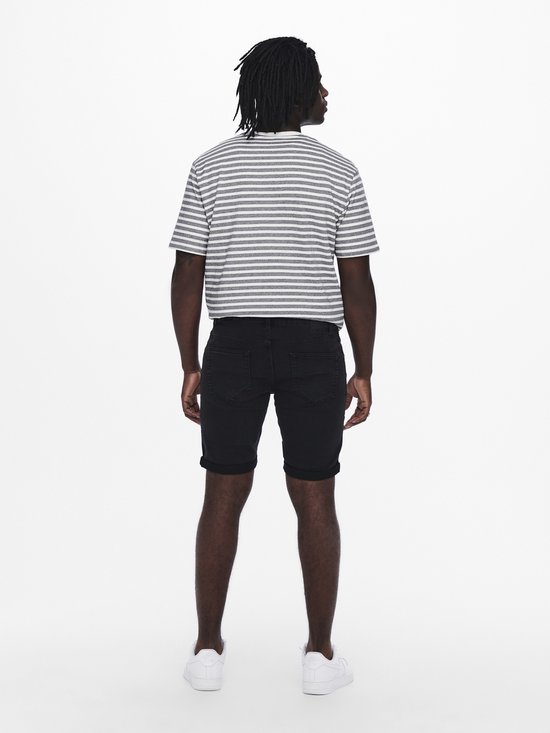 Man met gestreept t-shirt en zwarte denim shorts, witte sneakers, gezien van achteren.