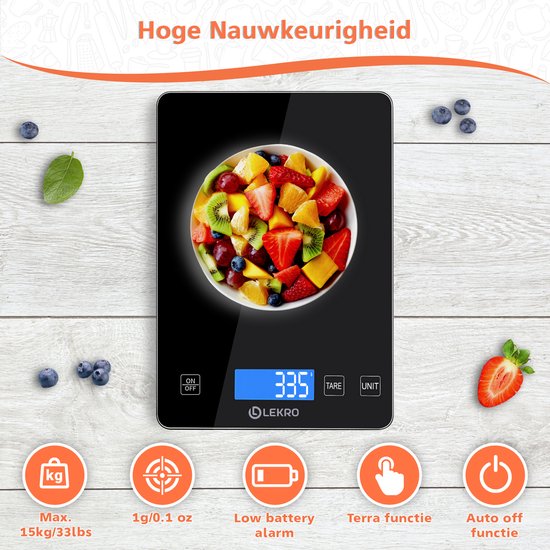 Zwarte keukenweegschaal met een fruitsalade erop, omringd door bosbessen en aardbei.