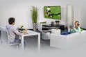 Woonkamer met man die krant leest en vrouw op tablet, tv aan muur met voetbalwedstrijd.