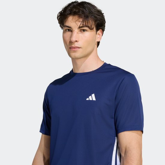 Man met donkerblauw T-shirt met witte Adidas logo's op borst en zijkanten.