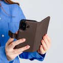 Een vrouw met een blauwe blouse houdt een bruin telefoonhoesje vast.