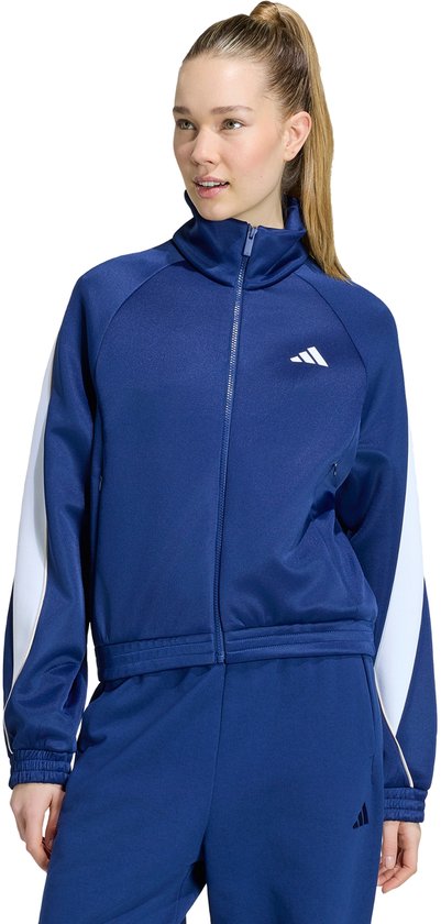 Model in blauw sportjack met witte strepen en trainingsbroek.