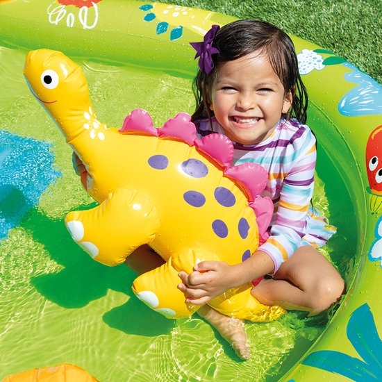 Een meisje met een gestreept zwempak houdt een gele dinosaurusknuffel vast in een opblaasbaar zwembad.