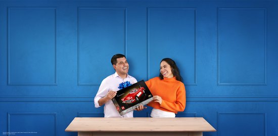 Een man en vrouw lachen terwijl ze naar een LEGO Chevrolet Corvette doos kijken. De man houdt de doos vast.