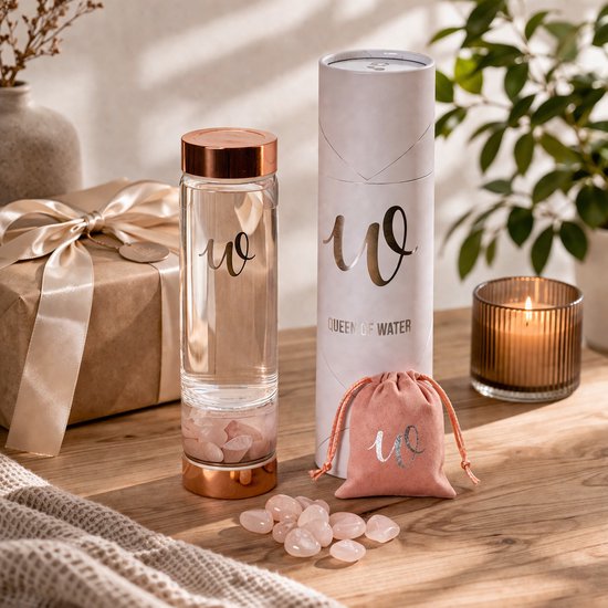 Glazen waterfles met koperkleurige dop, rozenkwarts, verpakking, cadeau en kaars.