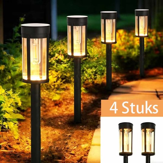 Vier staande solar tuinlampen met een glazen cilinder en bruin metalen frame, verlichten een pad langs groen gebladerte.