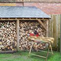 Een metalen zaagbok met kettingzaaghouder waarop twee houtblokken liggen. Op de achtergrond een houthok.