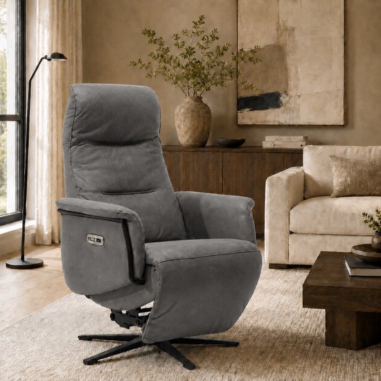 Grijze fauteuil in een woonkamer, met een sta-op functie en draaibaar onderstel.