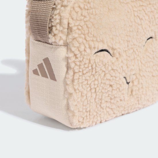 Gros plan d'un petit sac en peluche mouton beige avec un visage de mouton, avec un logo Adidas.