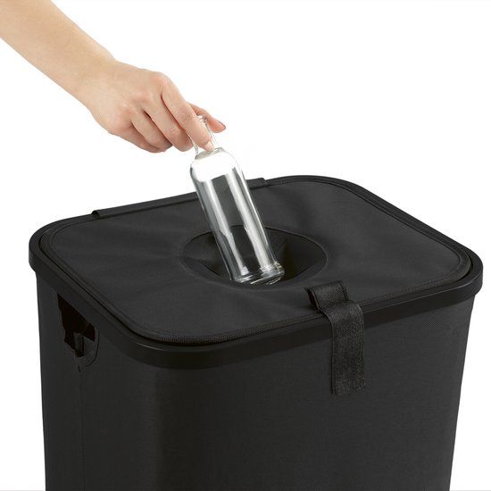 Hand deponeert een glazen fles in de opening van een zwarte flessenbak.
