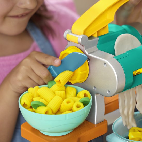 Kind maakt Play-Doh pasta met de machine, in een blauwe kom.