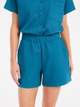 Close-up van een turquoise korte broek met elastische tailleband.