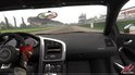 Gezichtspunt van binnenuit een Audi R8 op een circuit, met de hand van de bestuurder aan het stuur.