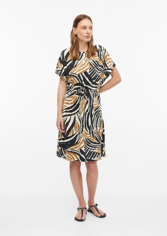 Jurk met korte mouwen, grafische print in zwart, wit en bruin, met ceintuur in de taille. Model staat frontaal.