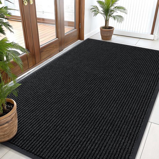 Grand tapis noir côtelé pour une entrée avec portes vitrées et plantes.