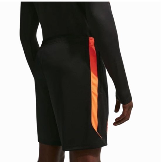 Achterkant van een zwarte Nike voetbalshort met een oranje zijstreep.