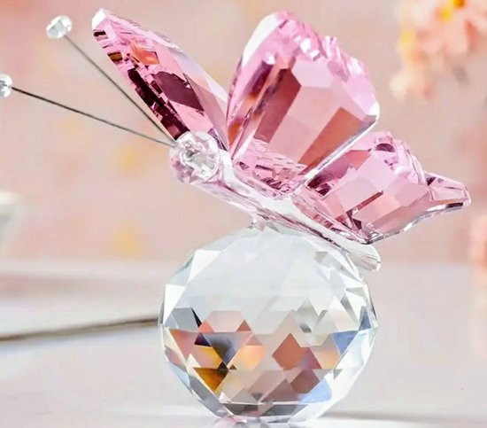 Roze kristallen vlinder met geslepen vleugels, zittend op een facetgeslepen kristallen bol.