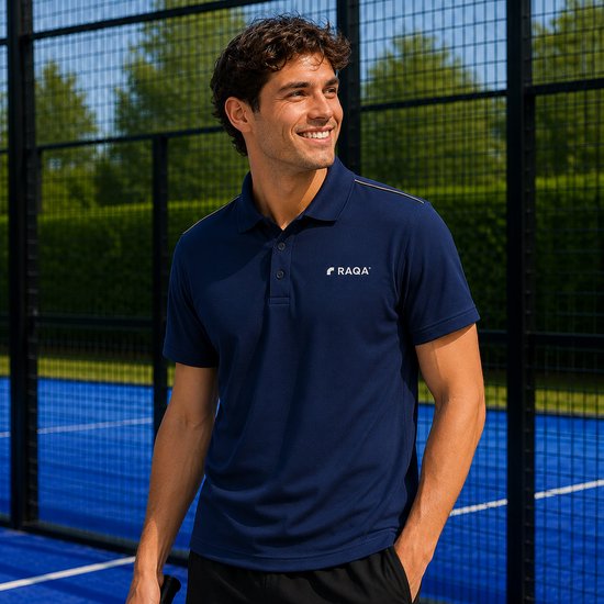 Man draagt een donkerblauwe sportpolo met korte mouwen en het Raqa-logo. Hij staat op een blauwe padelbaan met een racket.