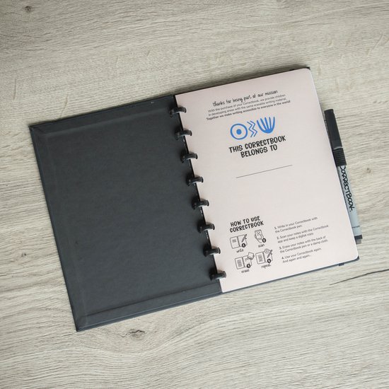 Een open zwart Correctbook notitieboek met een 'How to Use' pagina met instructies en illustraties.