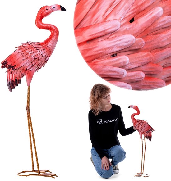 Statue de flamant rose en métal rose, avec un gros plan sur les plumes et une femme agenouillée à côté.