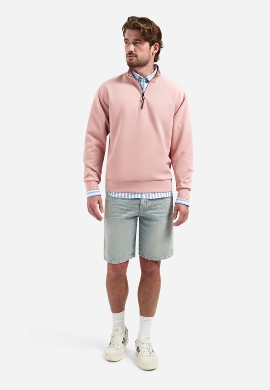 Man draagt blauw-wit gestreept linnen overhemd met een roze sweater erop
